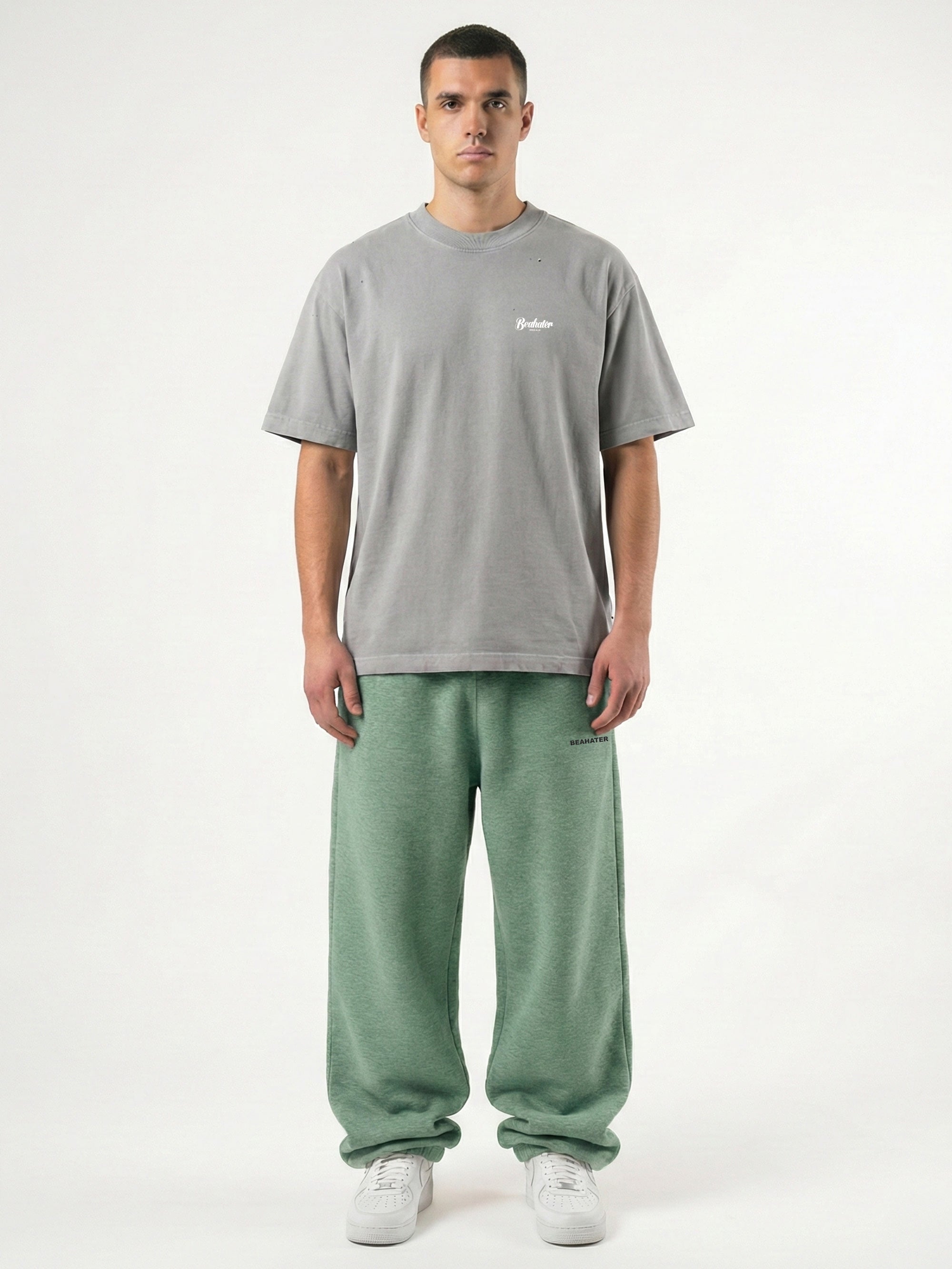 Baggy Jogger Sweatpants in Ash Grey mit Model in Frontansicht auf weißem Hintergrund, hochwertiger French Terry Stoff, entspannter Streetwear Fit mit elastischem Bund