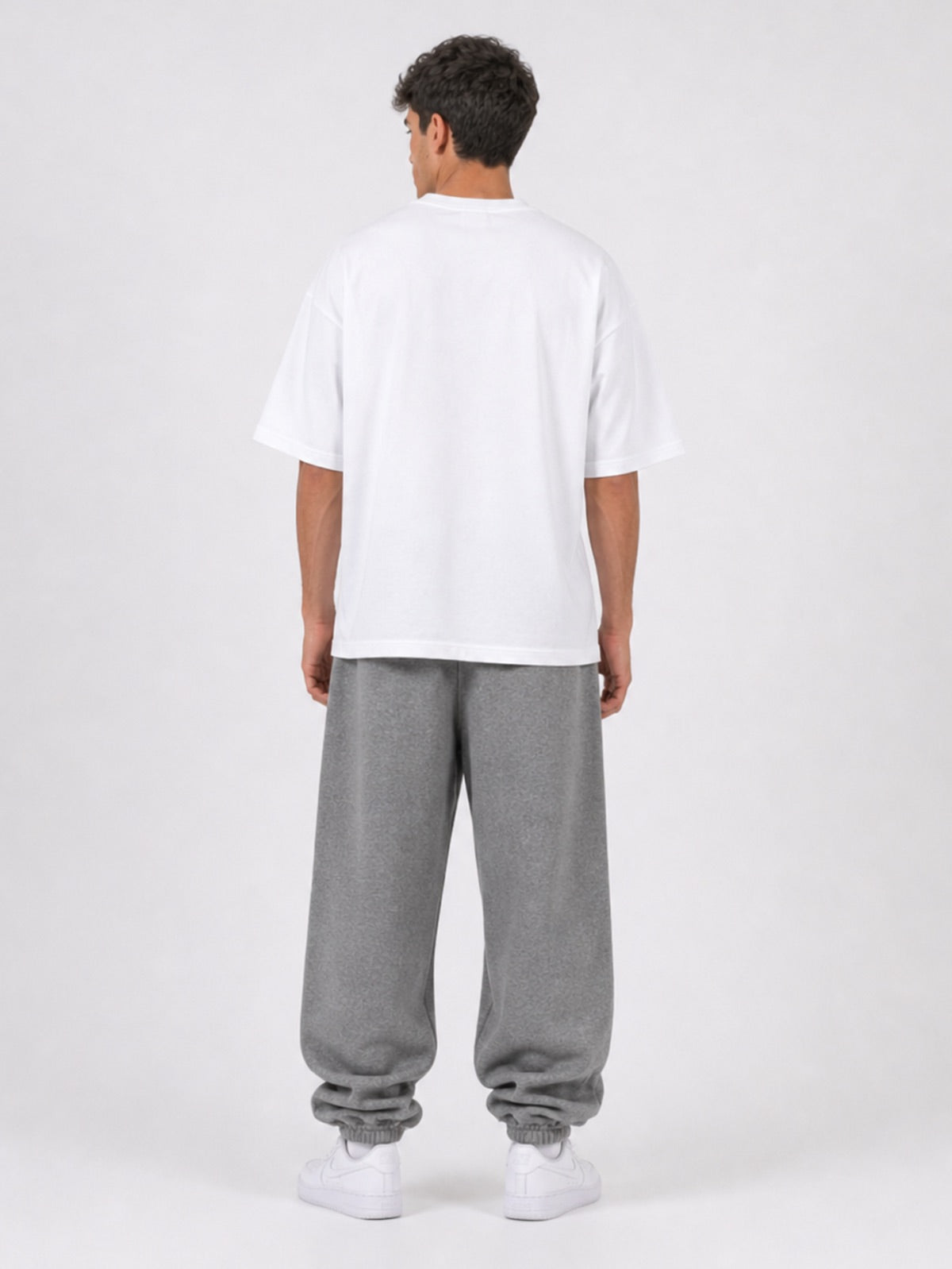 Frost Grey Jogginghose Rückansicht mit weißem Oversized T-Shirt und weißen Sneakern, Vollbild Studio