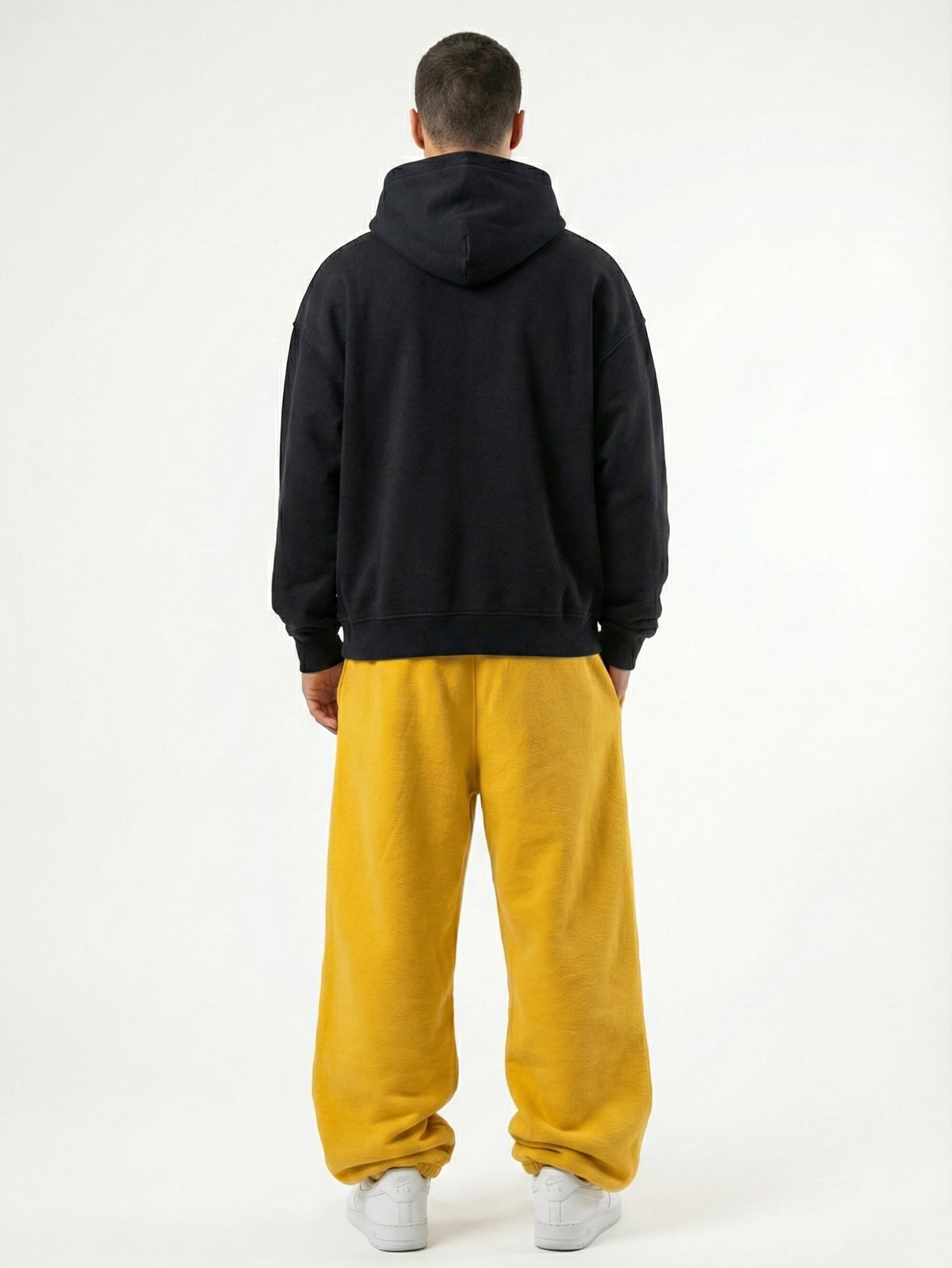 Baggy Jogger Sweatpants in Mustard Yellow an männlichem Model, Rückansicht auf weißem Hintergrund, hochwertiger French Terry Stoff im relaxed Streetwear Fit mit elastischem Bund