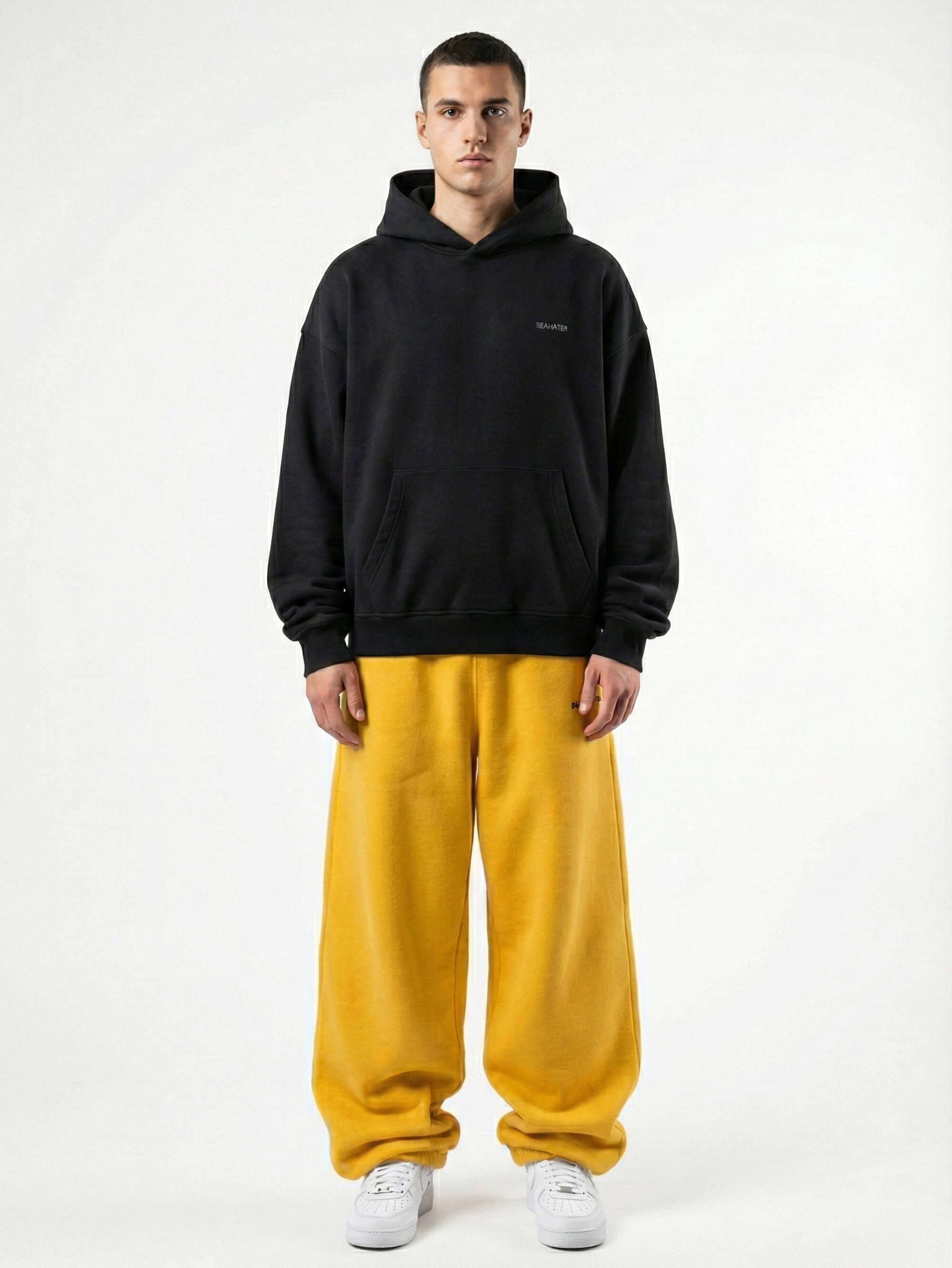 Baggy Jogger Sweatpants in Mustard Yellow am männlichen Model in Frontansicht auf weißem Hintergrund, weiter Streetwear Fit und elastischer Bund