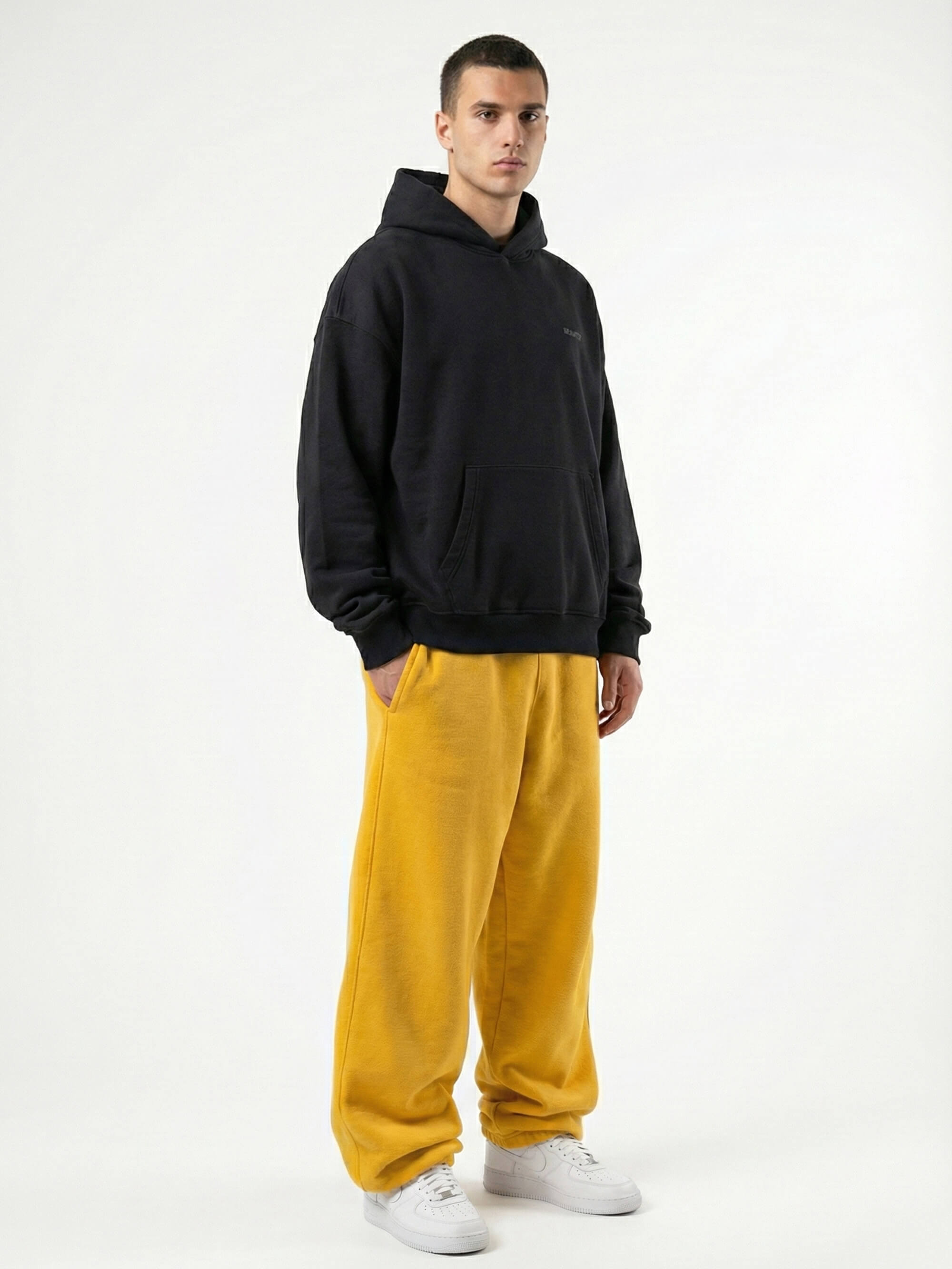 Baggy Jogger Sweatpants in Mustard Yellow am männlichen Model in seitlicher Ansicht auf weißem Hintergrund, weiter Streetwear Fit und elastischer Bund