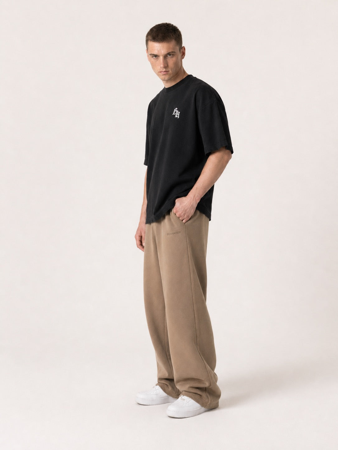 Schwarzes Oversized T-Shirt am Model mit beiger Hose, lockere Streetwear Silhouette, Dreiviertelansicht