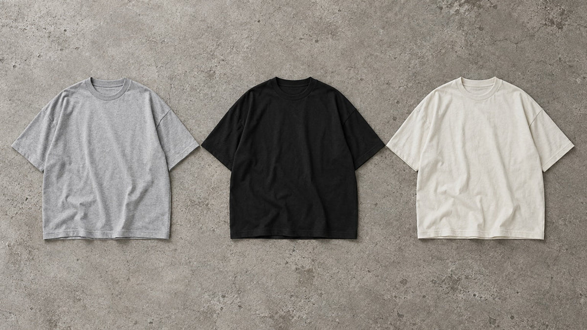 Editorial-Illustration: drei weit geschnittene T-Shirts in Grau, Schwarz und Off-White.