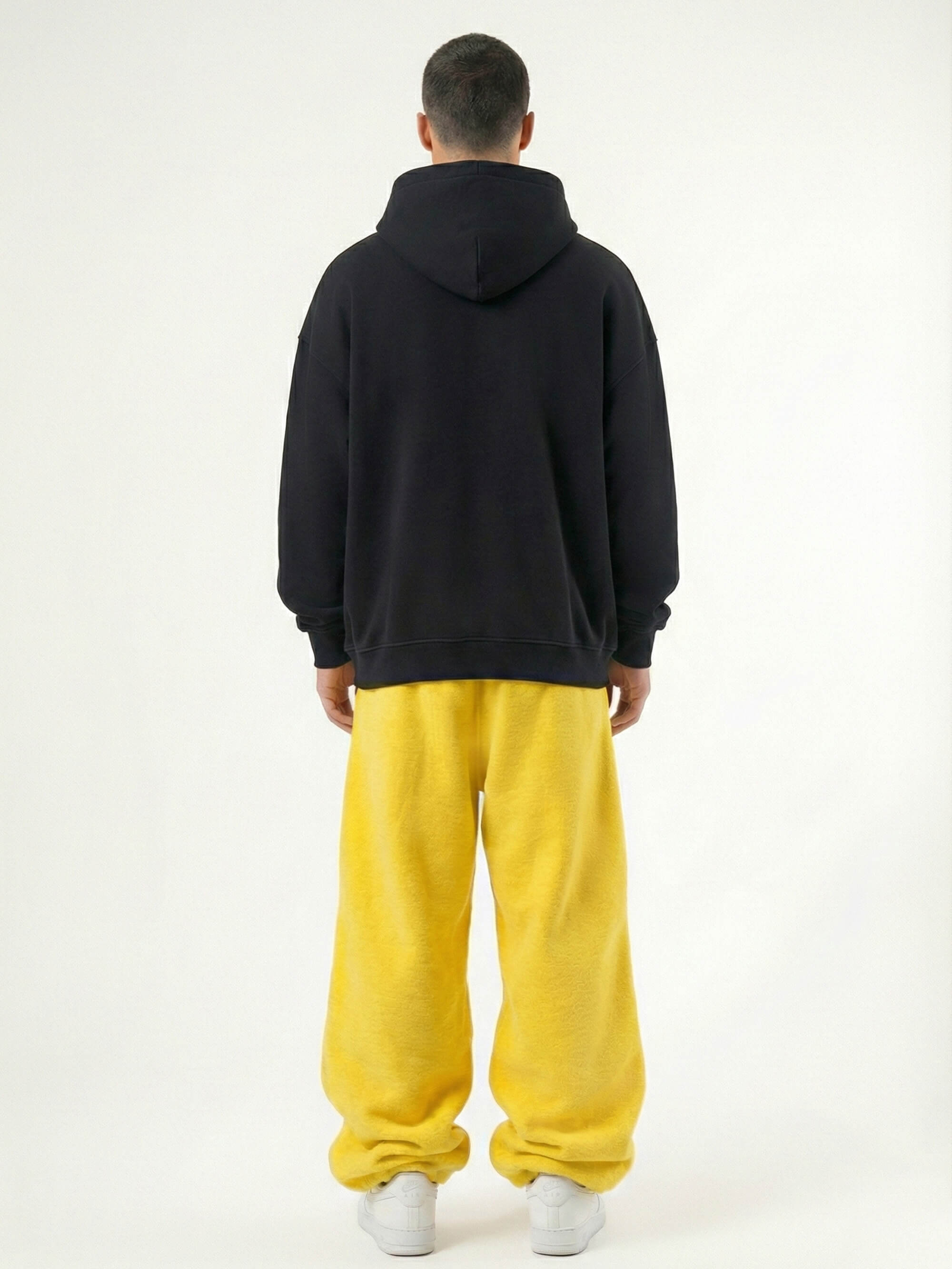 Baggy Jogger Sweatpants in Honey Yellow an einem männlichen Model, Rückansicht auf weißem Hintergrund, hochwertiger French Terry Stoff mit elastischem Bund und relaxed Streetwear Fit
