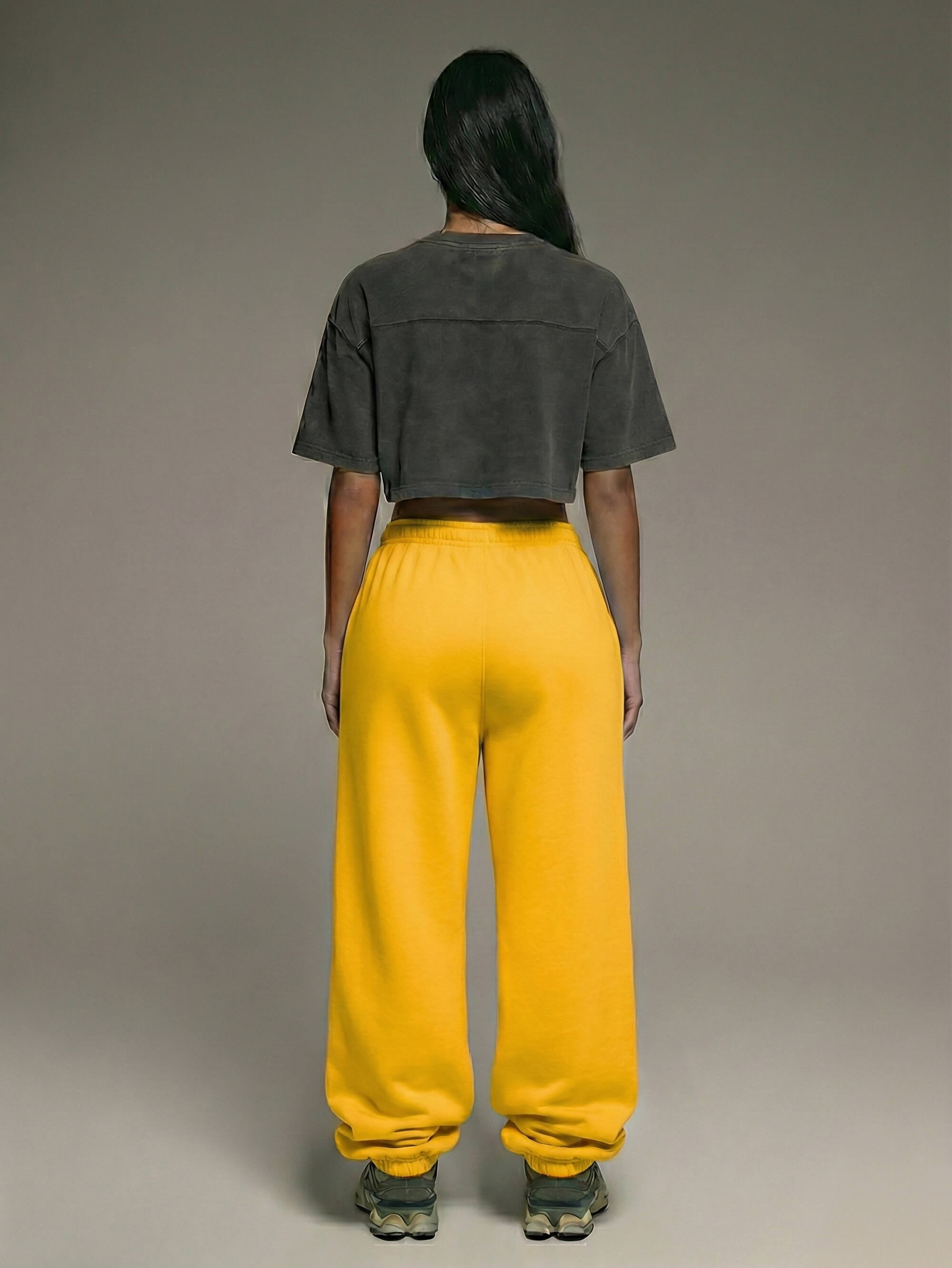 Baggy Jogger Mustard Yellow an weiblichem Model in Rückansicht, elastischer Bund, weiter Baggy Fit, gelber French Terry Stoff, entspannte Streetwear Silhouette.