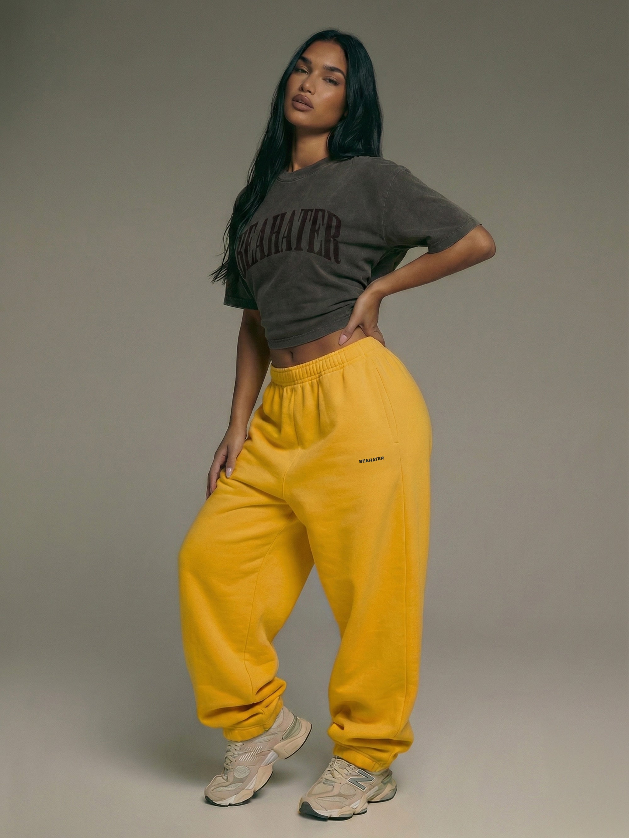 Baggy Jogger Mustard Yellow an weiblichem Model in Vorderansicht, weiter Baggy Fit mit elastischem Bund, weicher French Terry Stoff, Streetwear Look mit cropped Top.