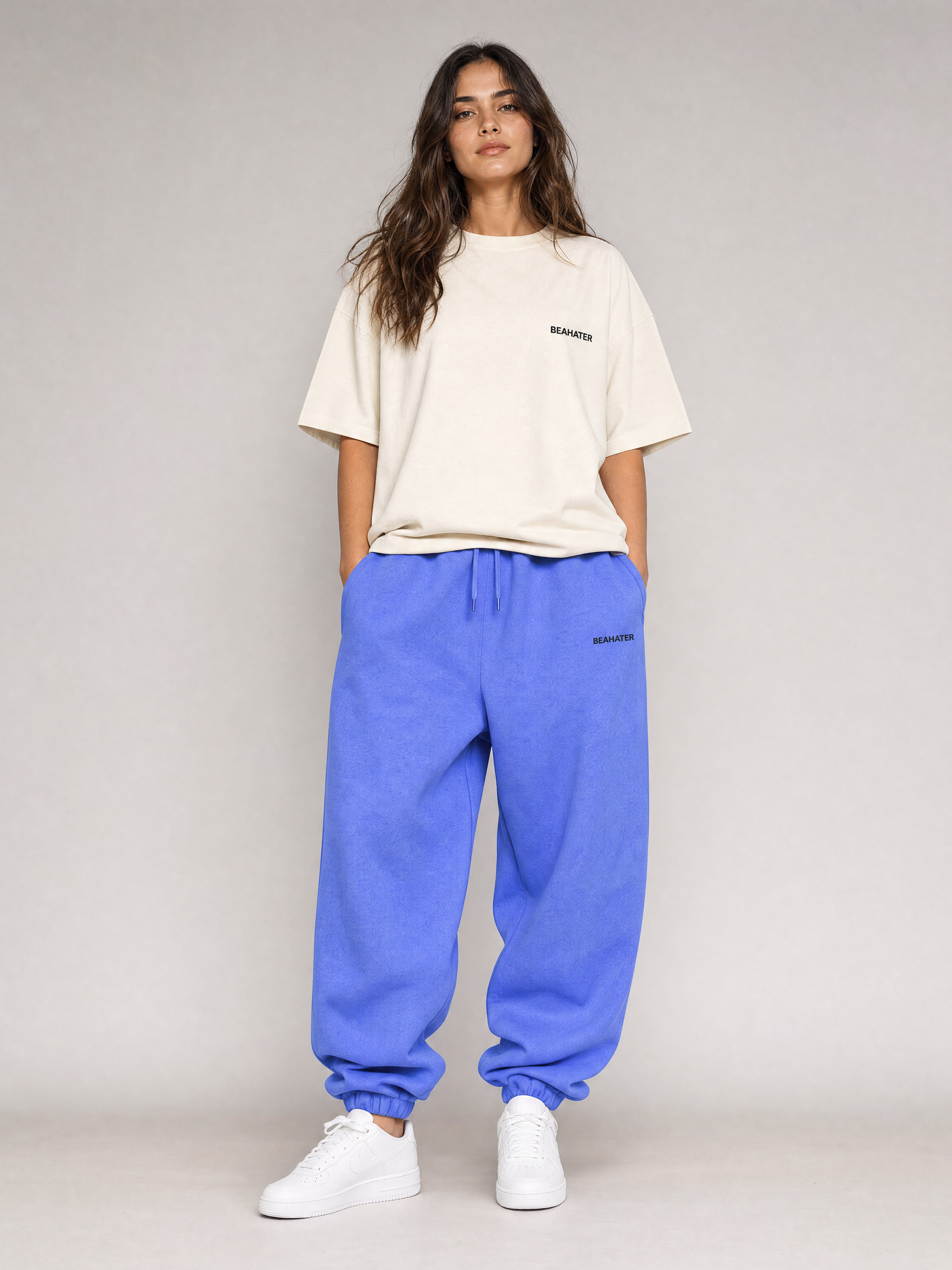 Baggy Jogger lila an weiblichem Model, Frontansicht, oversized Off-White Tee, weiße Sneaker