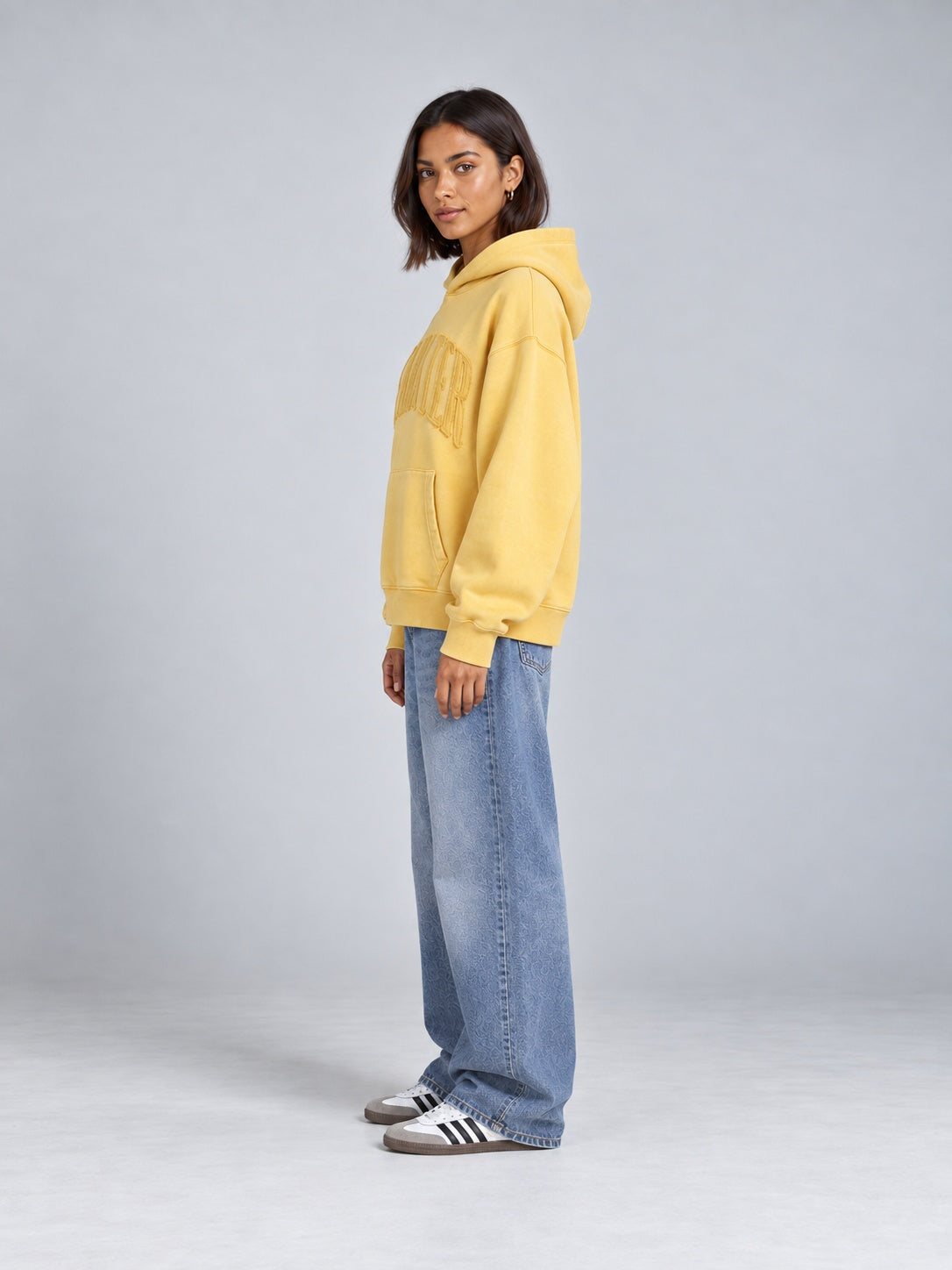 Gelber BEAHATER Oversized-Hoodie im Washed-Look am weiblichen Model, Seitenansicht mit locker fallendem Saum.