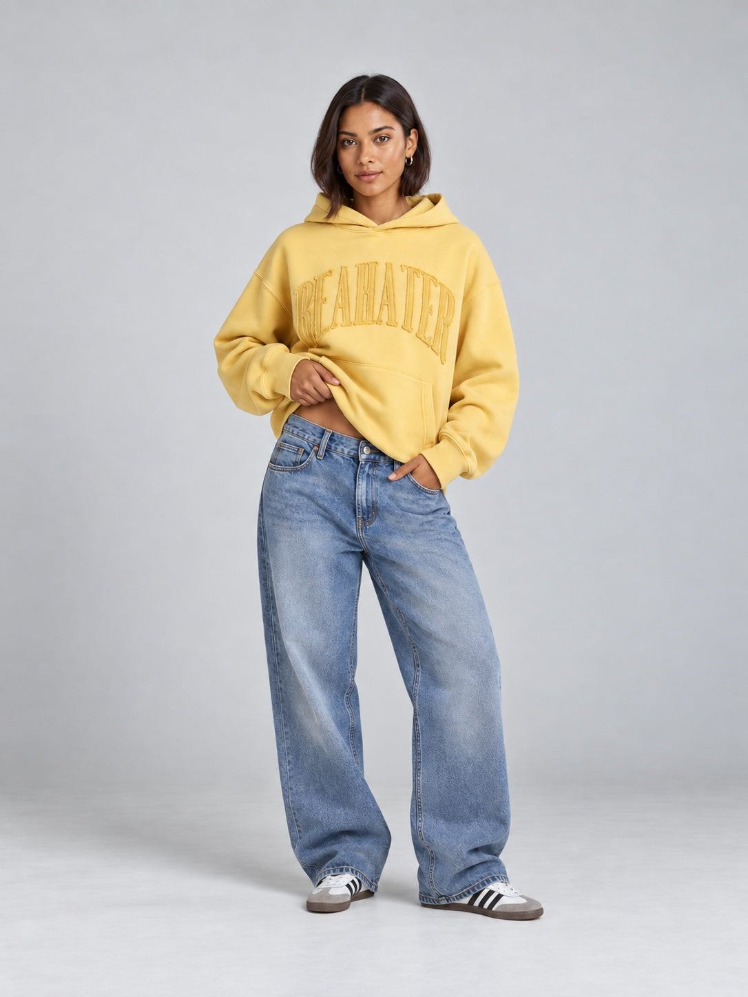 Gelber BEAHATER Oversized-Hoodie im Washed-Look am weiblichen Model, Vorderansicht mit leicht angehobenem Saum.