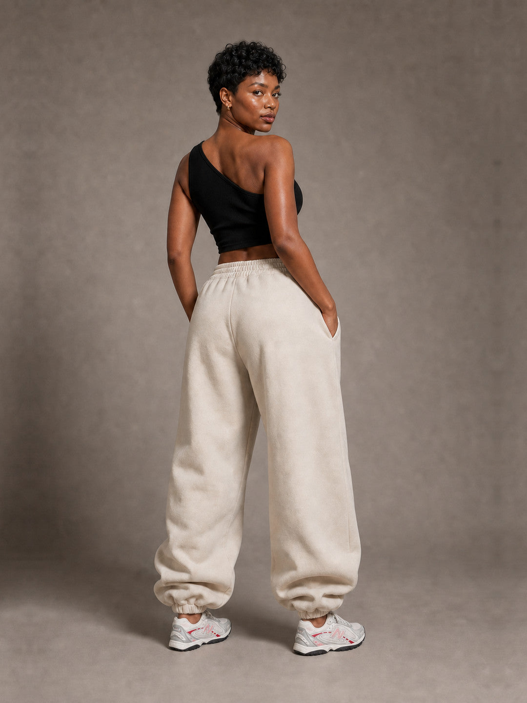 BEAHATER Relaxed Sweatpants Beige im Baggy-Fit – Rückenansicht mit silber-weißen Retro-Sneakern