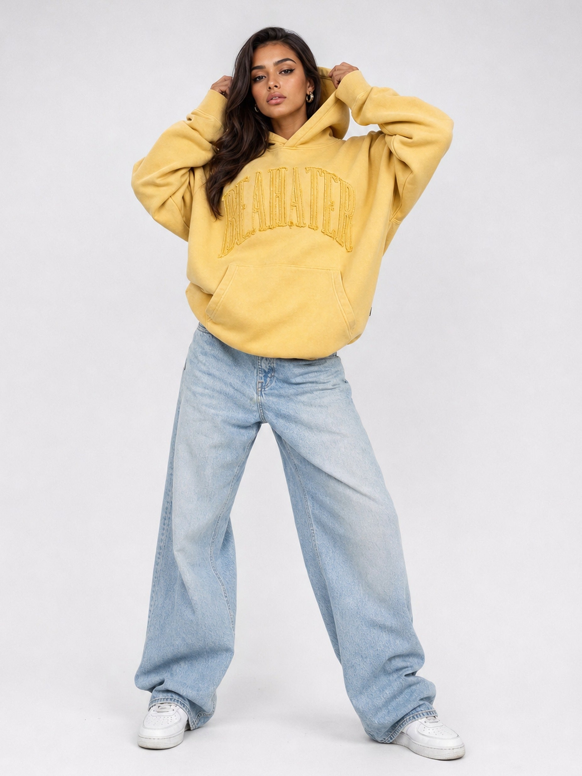 Senfgelber Oversized Hoodie mit Arch-Stickerei am weiblichen Model, garment-dyed Washed Finish, schwerer French Terry