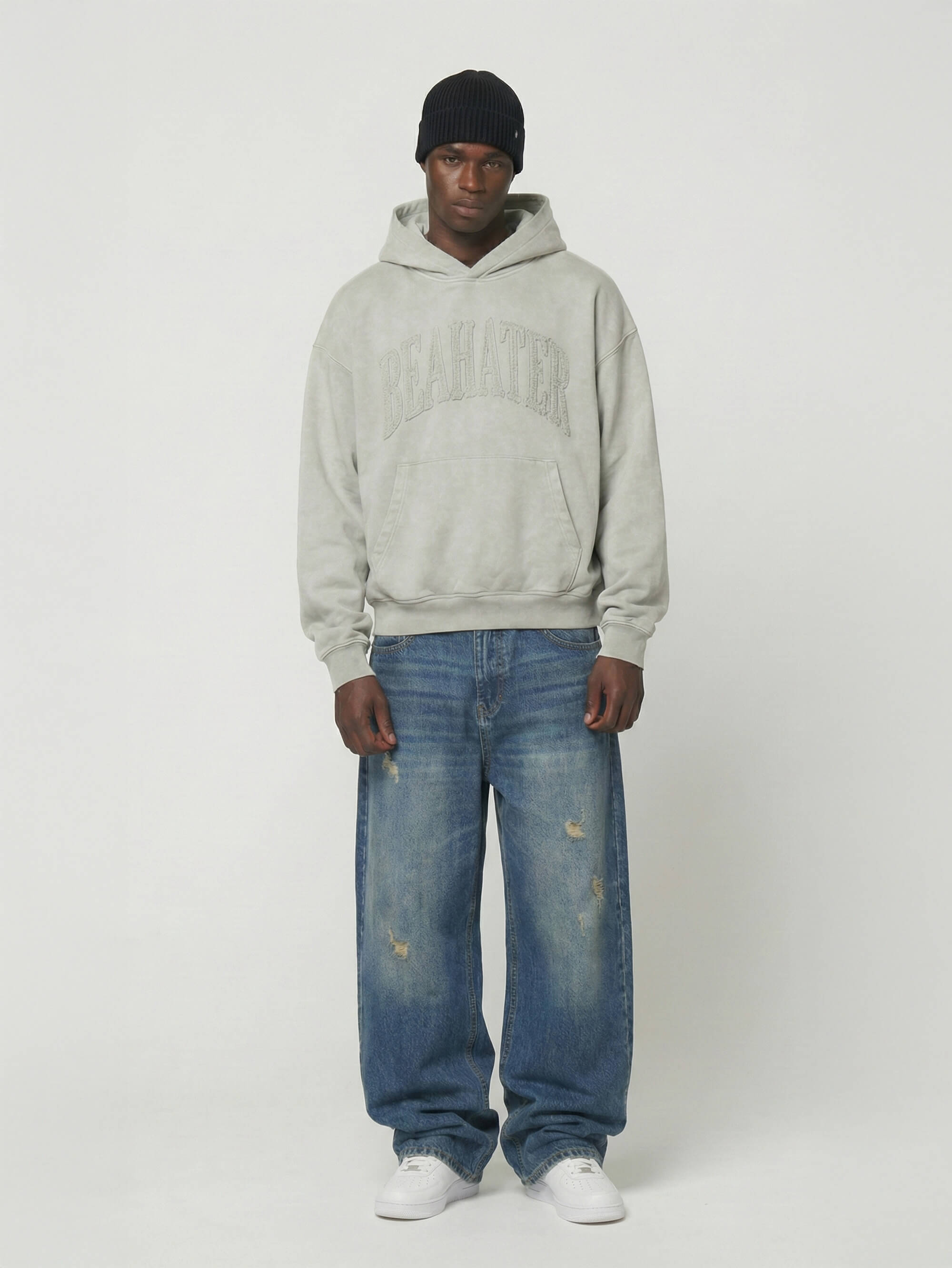 Model trägt BEAHATER Oversized Hoodie Vintage Grey in Frontansicht – Washed Look, Kängurutasche, 2D Stickerei

