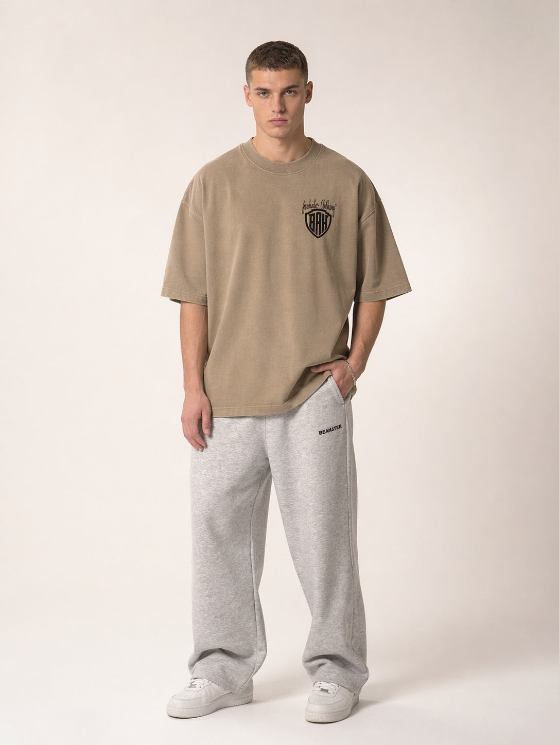 Stone-farbenes Oversized T-Shirt Herren mit Wappen-Logo Stickerei auf der Brust, Frontansicht am Model