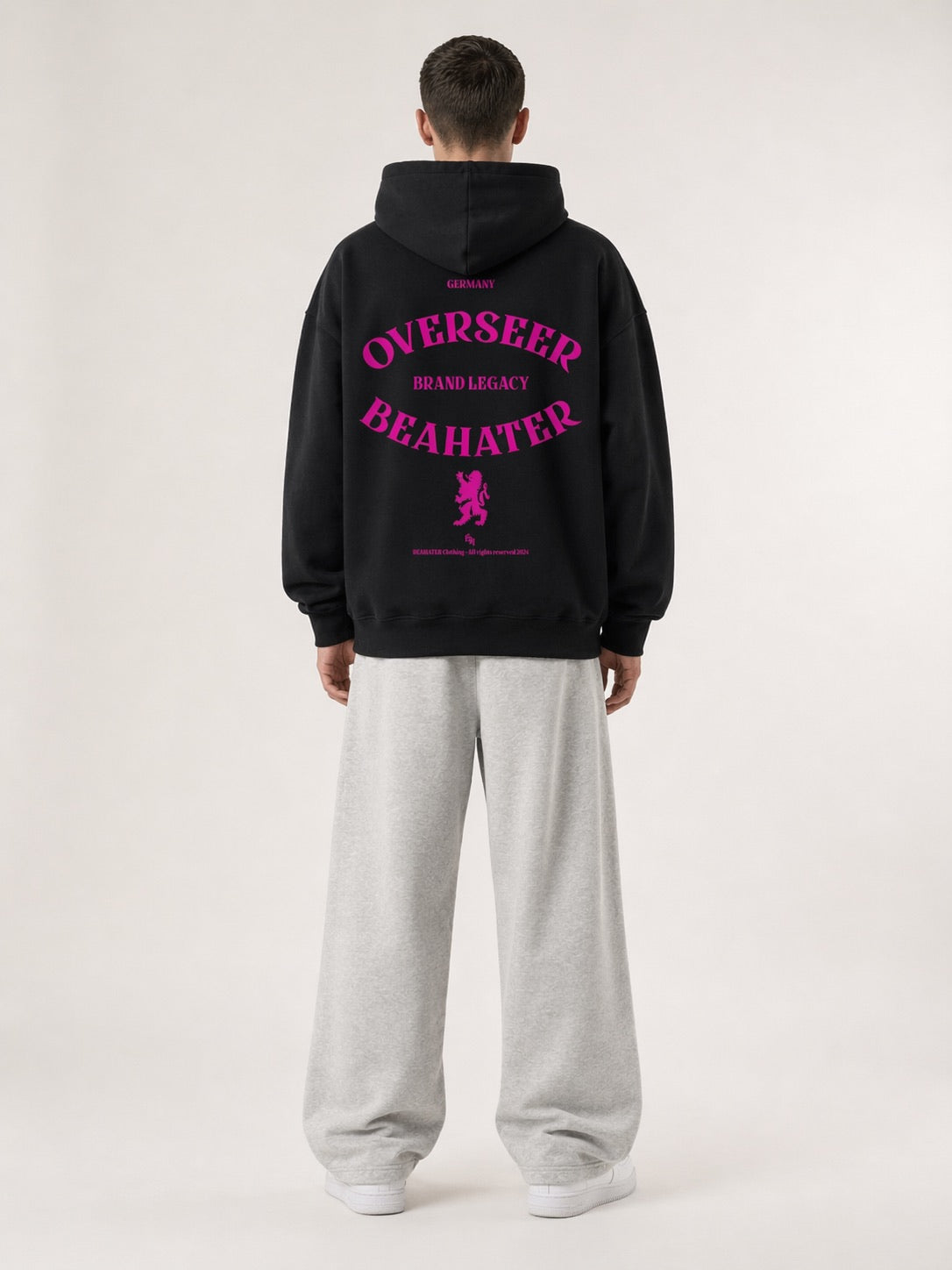 Schwarzer Oversized Hoodie Rückansicht mit Overseer-Print in Neon-Pink, Löwenwappen, Streetwear Herren